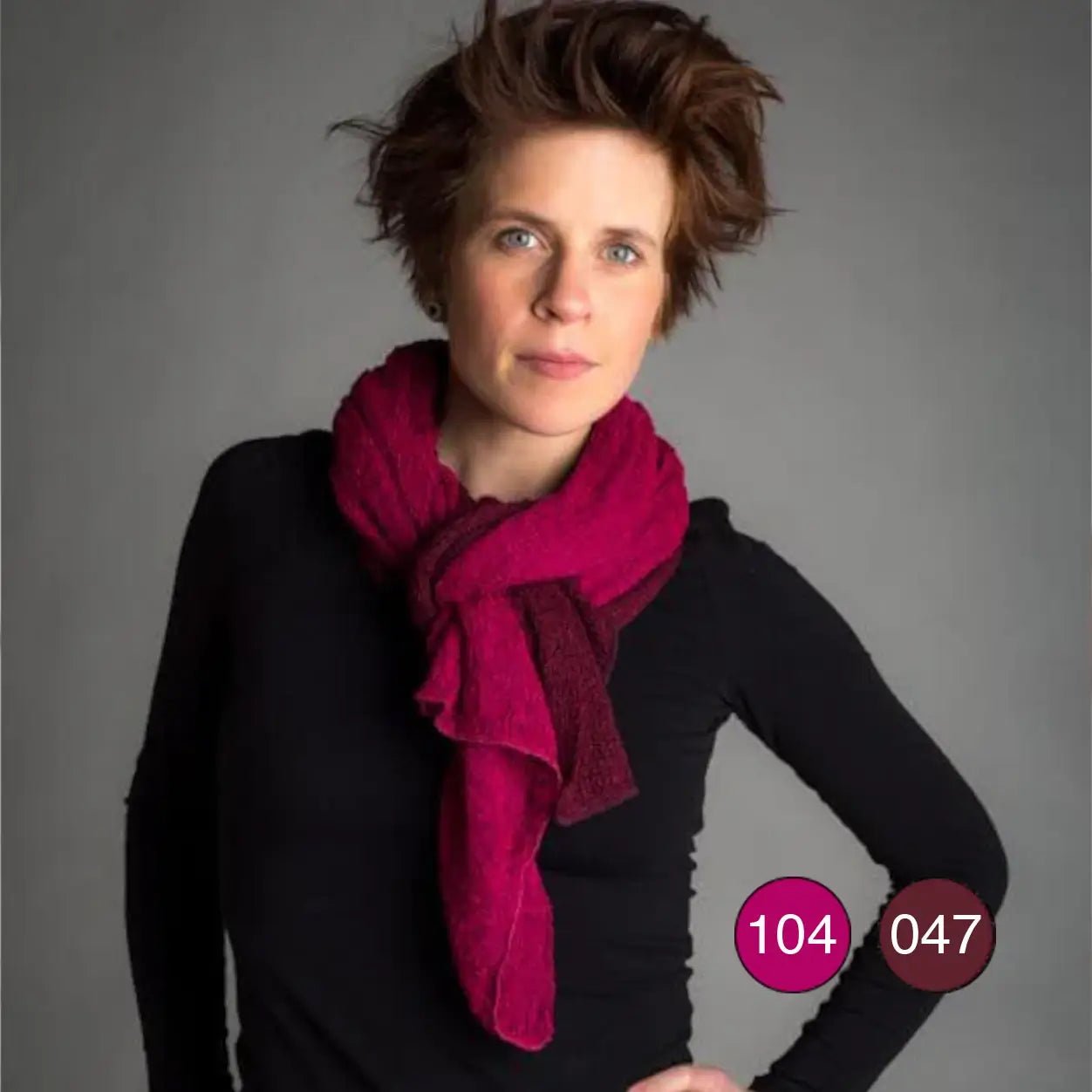 Kvinna i mörk topp som bär två Almira-sjalar samtidigt, en i fuchsia och en i bourdeaux; de finstickade sjalarna draperas runt halsen och visar hur färgerna kan kombineras. Ulla Jacobsson Kläder