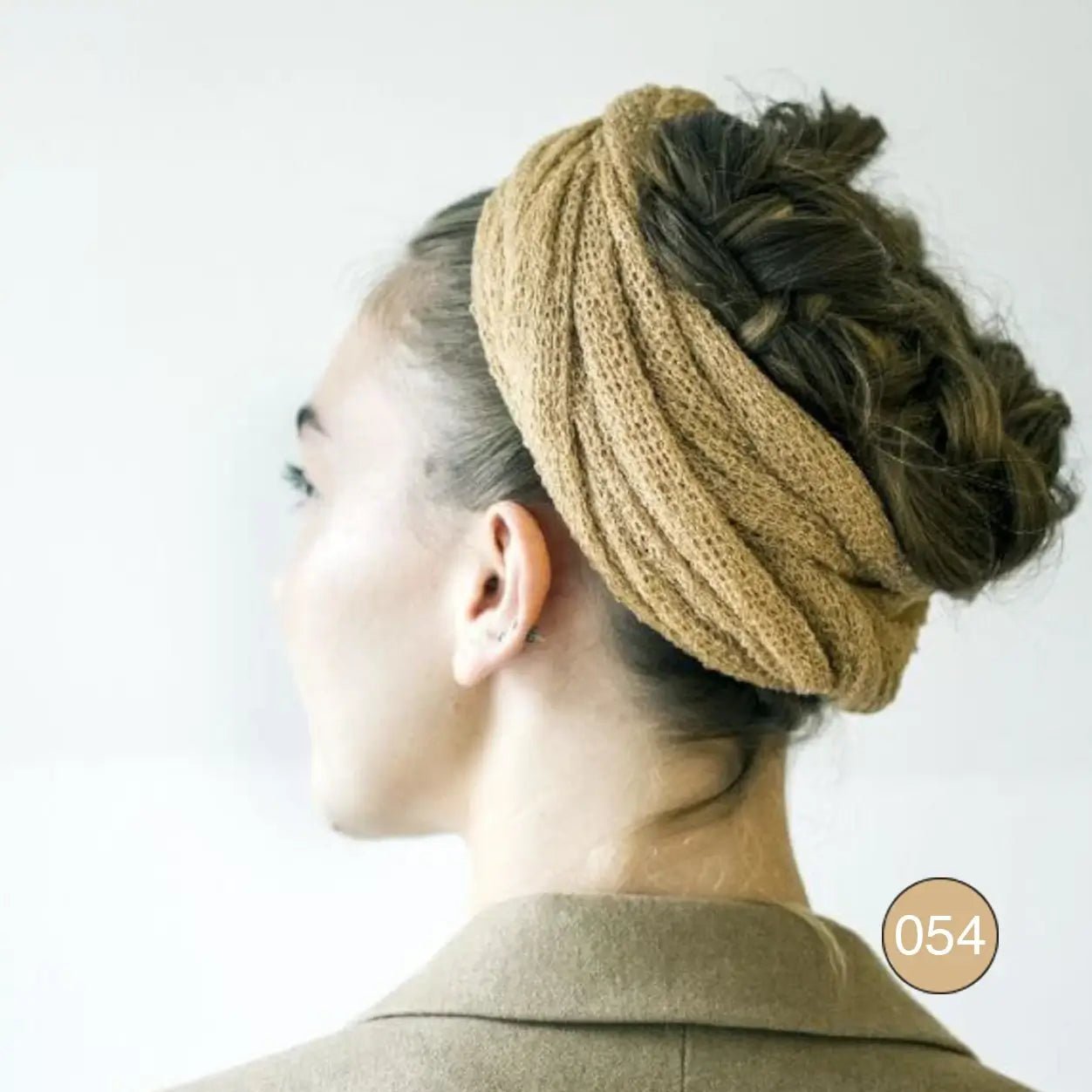 Kvinna i profil som bär en Almira sjal i kamel virad som en turban kring håret; det mjuka stickade garnet visar hur sjalen även kan bäras som huvudbonad. Ulla Jacobsson Kläder