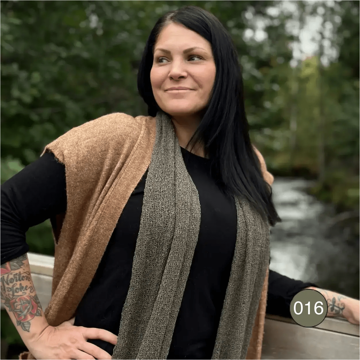 Almira sjal i lavgrön ton lagd dubbel runt halsen på en kvinna, med ändarna samlade framtill; den finstickade ytan skiftar varmt i ljuset. Ulla Jacobsson Kläder