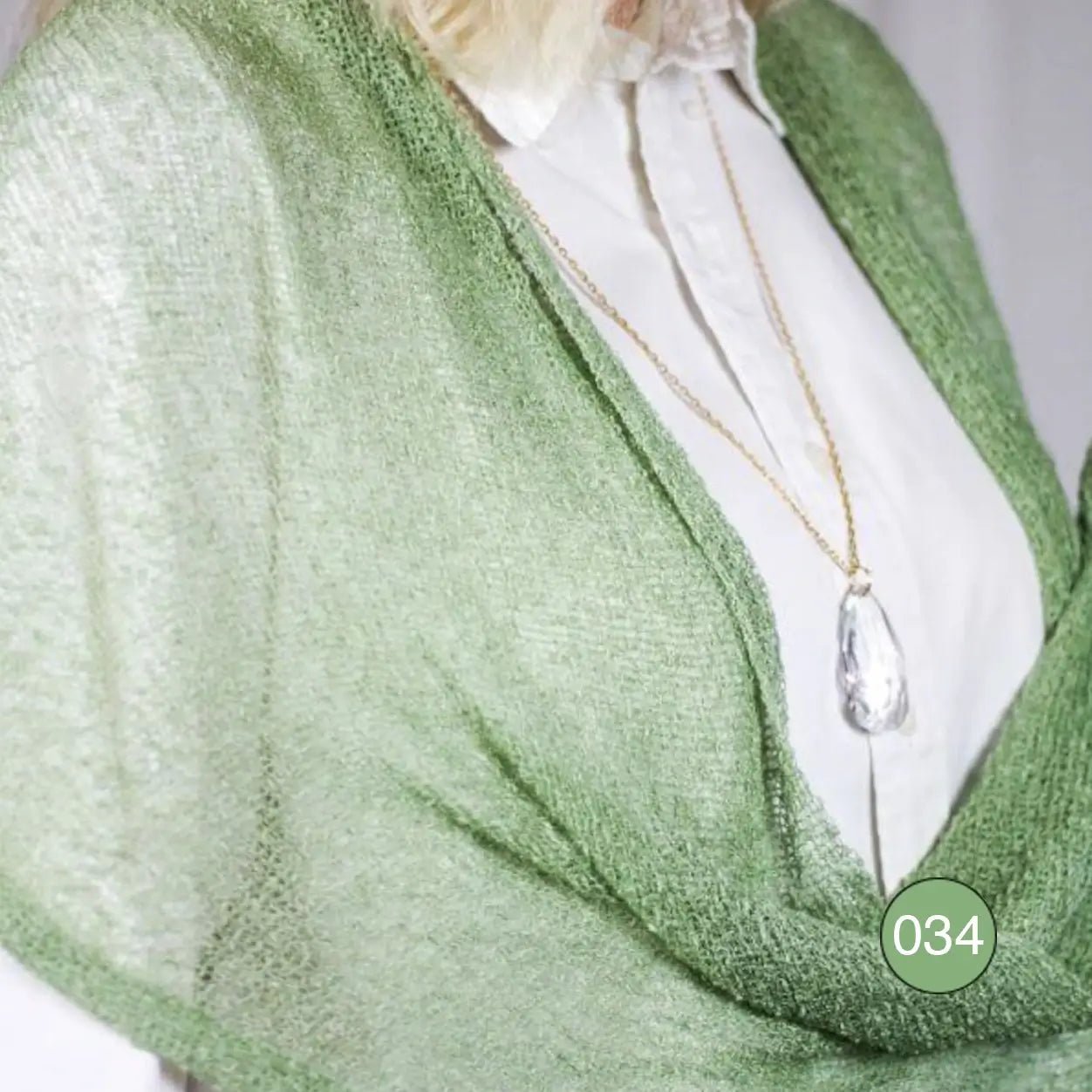 Närbild på den finstickade Almira-sjalen i ljusgrön ton, där det luftiga garnets maskor och mjuka fall syns i detalj – Ulla Jacobsson Kläder.