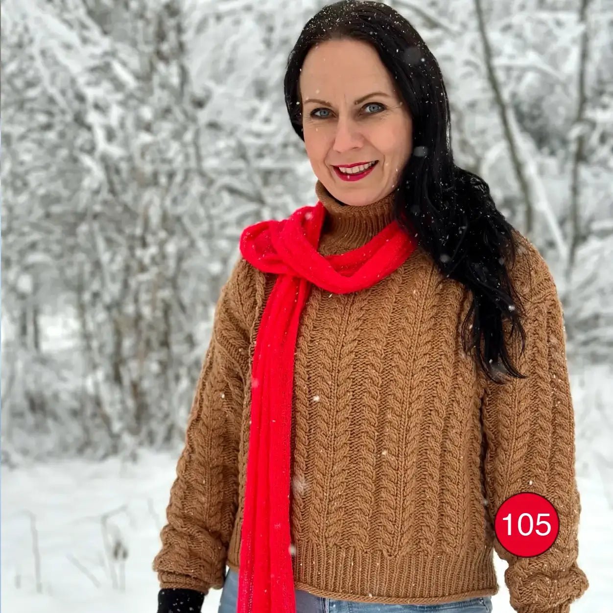 Kvinna i en klarblå topp med en Almira sjal i signalröd ton draperad runt halsen; det starka röda garnet ramar in ansiktet och faller nedför bröstet. Ulla Jacobsson Kläder