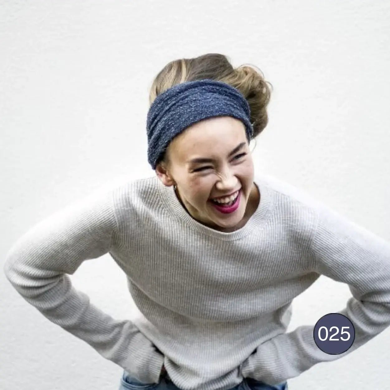 Skrattande kvinna med handen i sidan och en jeansblå Eva tubsjal buren som hårband; ledig grå stickad tröja. Ulla Jacobsson Kläder